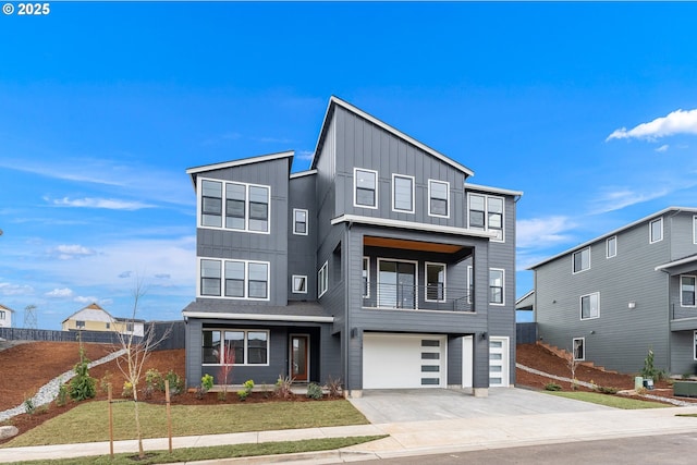 contemporary home featuring concrete driveway, a balcony, an attached garage, board and batten siding, and a front yard