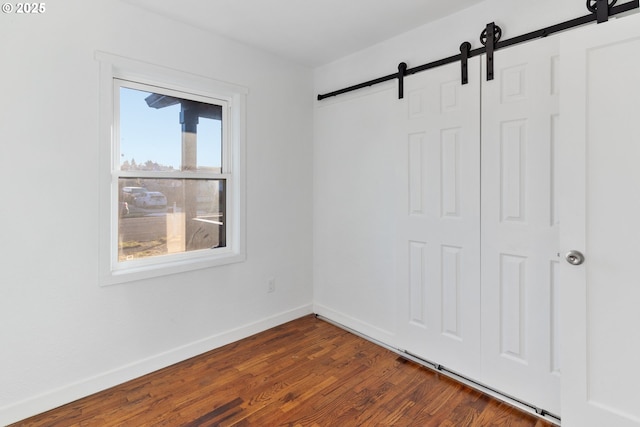 unfurnished room with dark wood-type flooring and a barn door