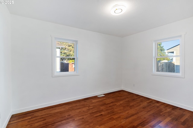 unfurnished room featuring plenty of natural light and dark hardwood / wood-style floors