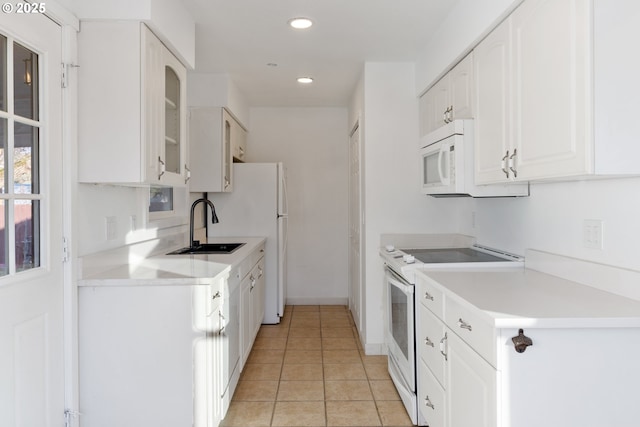 kitchen with sink, white appliances, light tile patterned floors, and white cabinets