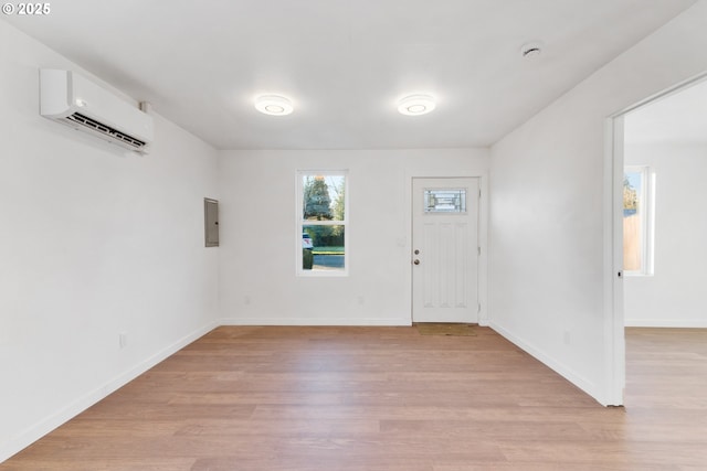 entryway with light hardwood / wood-style flooring, electric panel, and an AC wall unit