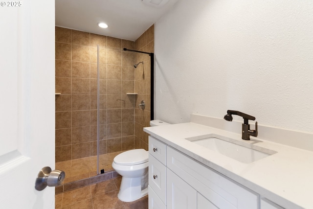 bathroom featuring a tile shower, vanity, tile patterned floors, and toilet