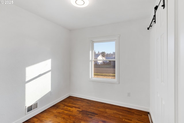 spare room with dark hardwood / wood-style floors and a barn door