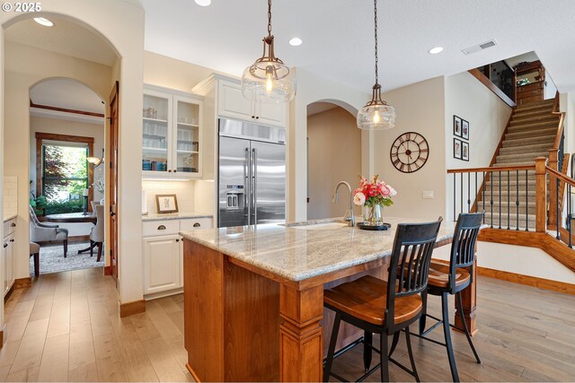 kitchen featuring visible vents, arched walkways, light wood-style floors, and stainless steel built in refrigerator