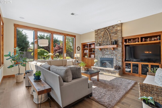 living room featuring baseboards, a fireplace, wood finished floors, and visible vents