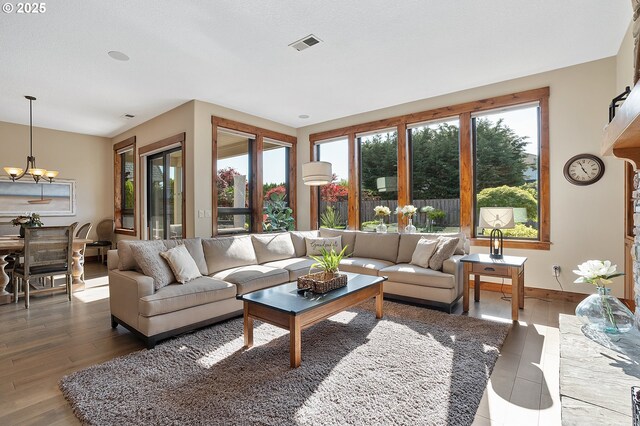 living area with a chandelier, baseboards, visible vents, and wood finished floors