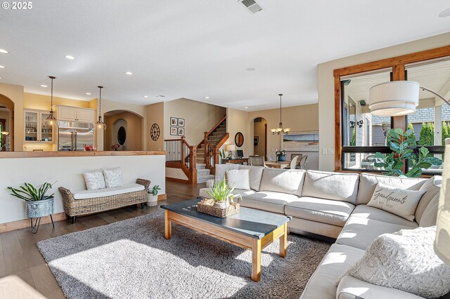 living area featuring arched walkways, stairs, recessed lighting, wood finished floors, and visible vents