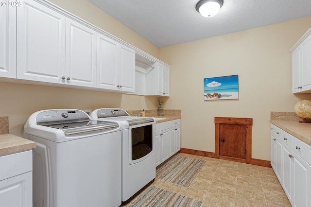 laundry area with a sink, baseboards, washing machine and dryer, and cabinet space