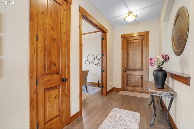 foyer entrance featuring baseboards and light wood finished floors