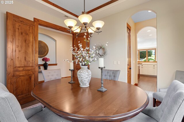 dining space with arched walkways, a notable chandelier, recessed lighting, and wood finished floors