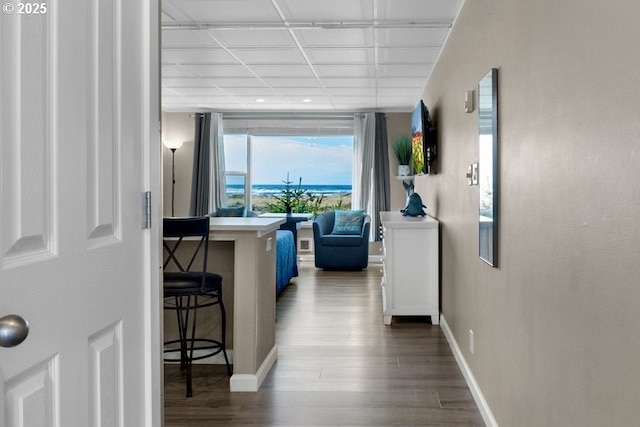corridor featuring dark wood-type flooring and baseboards