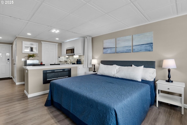 bedroom with recessed lighting, light wood-style flooring, and baseboards