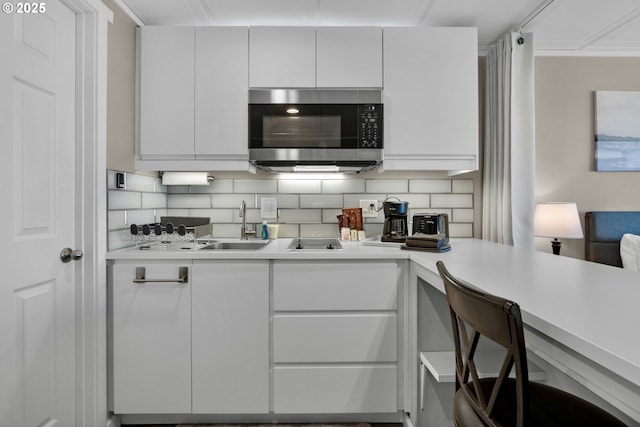 kitchen with stainless steel microwave, light countertops, decorative backsplash, and white cabinetry