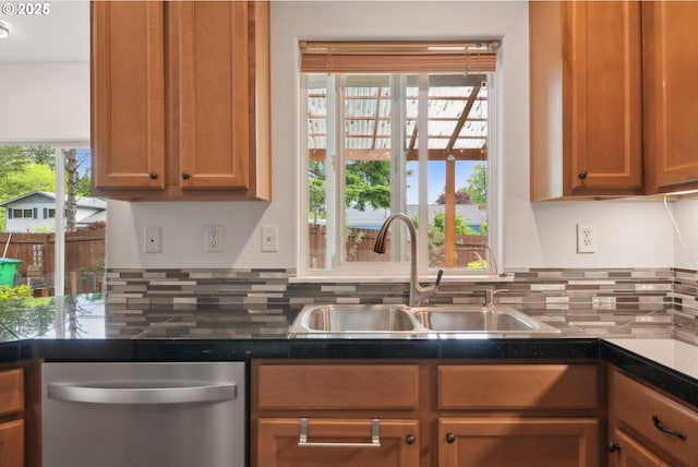 kitchen featuring dishwasher, a sink, decorative backsplash, and dark countertops