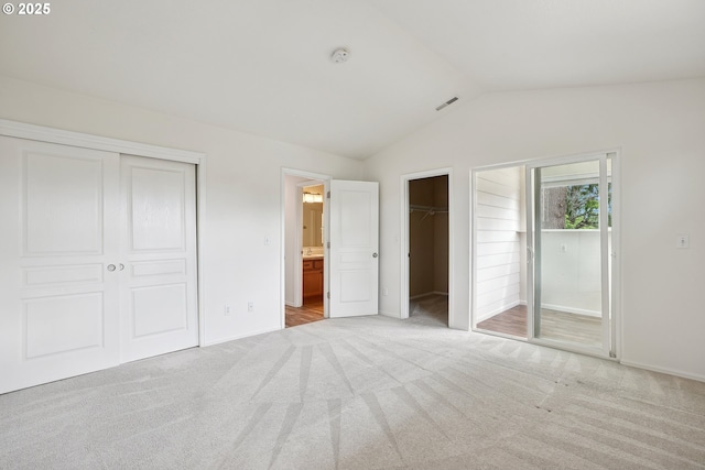 unfurnished bedroom featuring vaulted ceiling, carpet flooring, baseboards, a closet, and ensuite bathroom