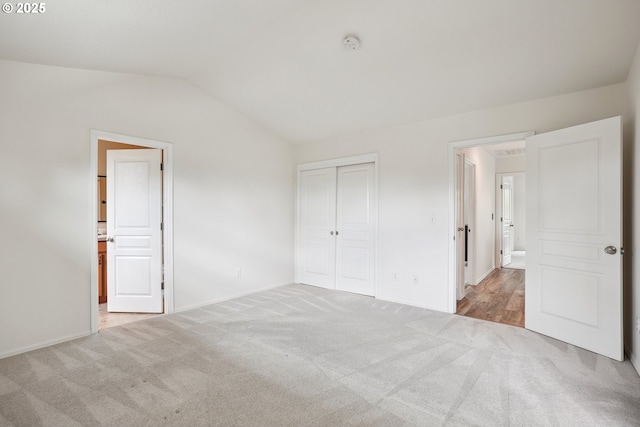 unfurnished bedroom with carpet floors, vaulted ceiling, a closet, baseboards, and ensuite bathroom