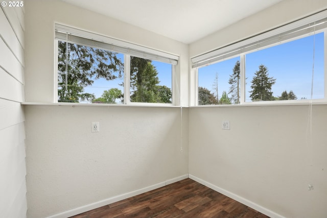 unfurnished room with plenty of natural light, baseboards, and dark wood-style floors