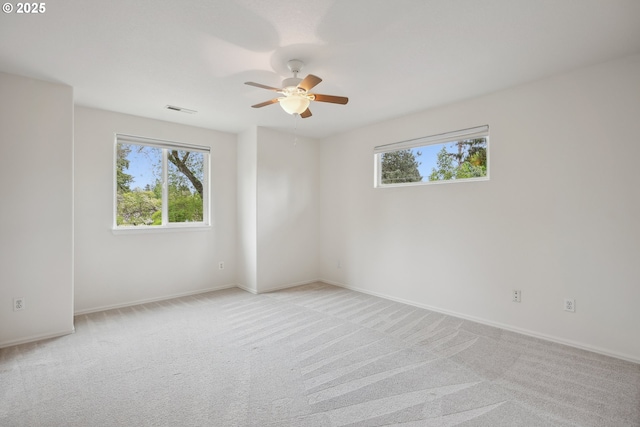 spare room with healthy amount of natural light, a ceiling fan, light carpet, and baseboards