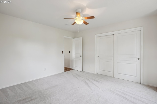 unfurnished bedroom featuring carpet, a closet, baseboards, and a ceiling fan