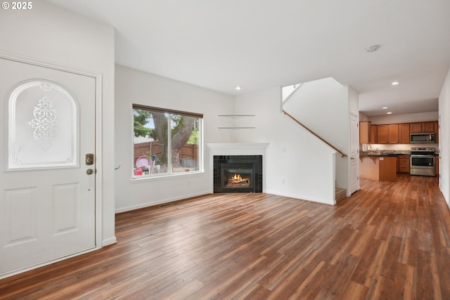 unfurnished living room featuring wood finished floors, recessed lighting, a tile fireplace, baseboards, and a sink