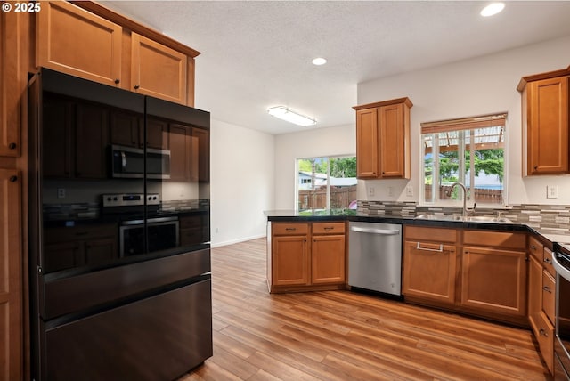kitchen featuring appliances with stainless steel finishes, a sink, recessed lighting, dark countertops, and a peninsula