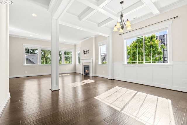 16944 SW Birdsong St, Beaverton, OR 97007 - unfurnished living room with a chandelier, beam ceiling, wood finished floors, a wainscoted wall, and a lit fireplace