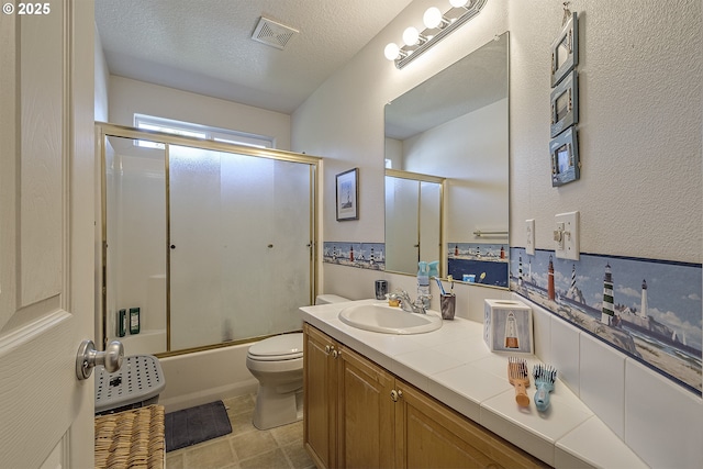 bathroom featuring a textured ceiling, toilet, vanity, visible vents, and combined bath / shower with glass door