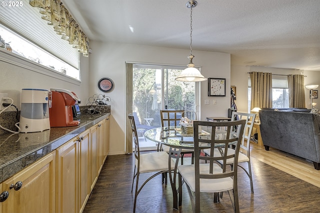 dining space featuring a textured ceiling, dark wood-type flooring, and a healthy amount of sunlight