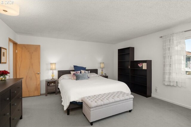 bedroom featuring a textured ceiling, baseboards, and light carpet