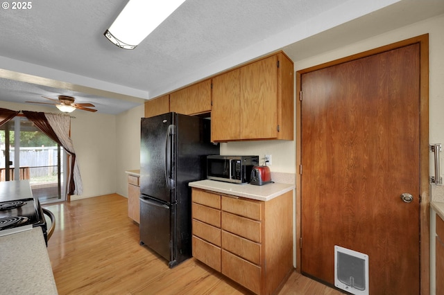 945 Irving Ct, Eugene, OR 97404 - kitchen with black appliances, light wood-type flooring, light countertops, a ceiling fan, and heating unit