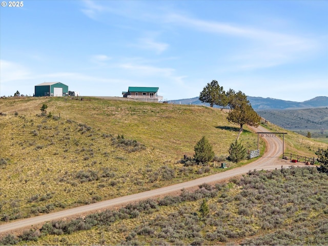 view of yard with a rural view, a mountain view, and a detached garage