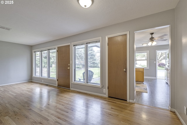 doorway to outside featuring wood finished floors, baseboards, ceiling fan, and a textured ceiling