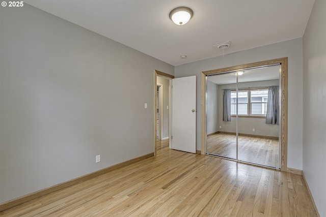 unfurnished bedroom with light wood-style flooring, a closet, and baseboards