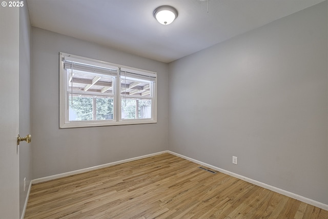 spare room with baseboards and light wood-style floors