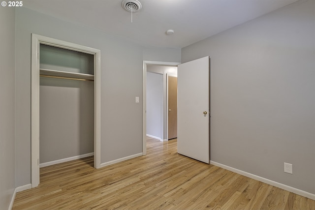 unfurnished bedroom featuring light wood finished floors, baseboards, and a closet