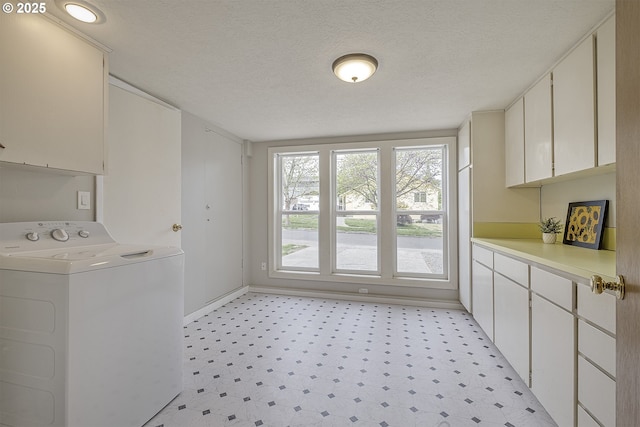 clothes washing area with washer / dryer, cabinet space, a textured ceiling, baseboards, and light floors