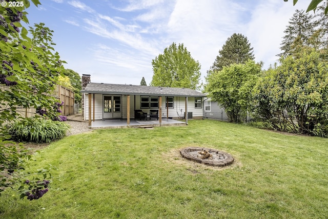 back of property with a chimney, a patio area, and an outdoor fire pit