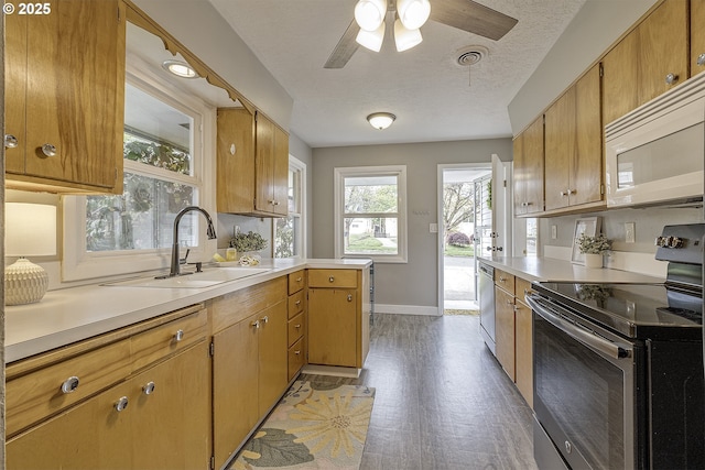 kitchen featuring appliances with stainless steel finishes, light countertops, a sink, baseboards, and a textured ceiling