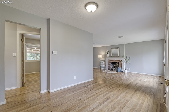 unfurnished living room featuring light wood-type flooring, baseboards, and a brick fireplace