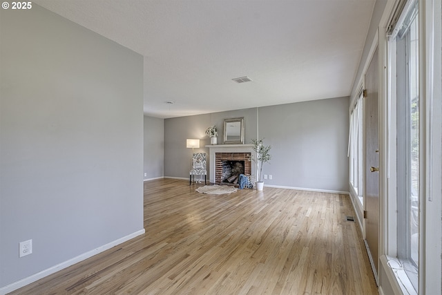 unfurnished living room featuring light wood-style floors, baseboards, and a fireplace
