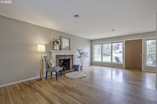 living room with wood finished floors, baseboards, and a brick fireplace