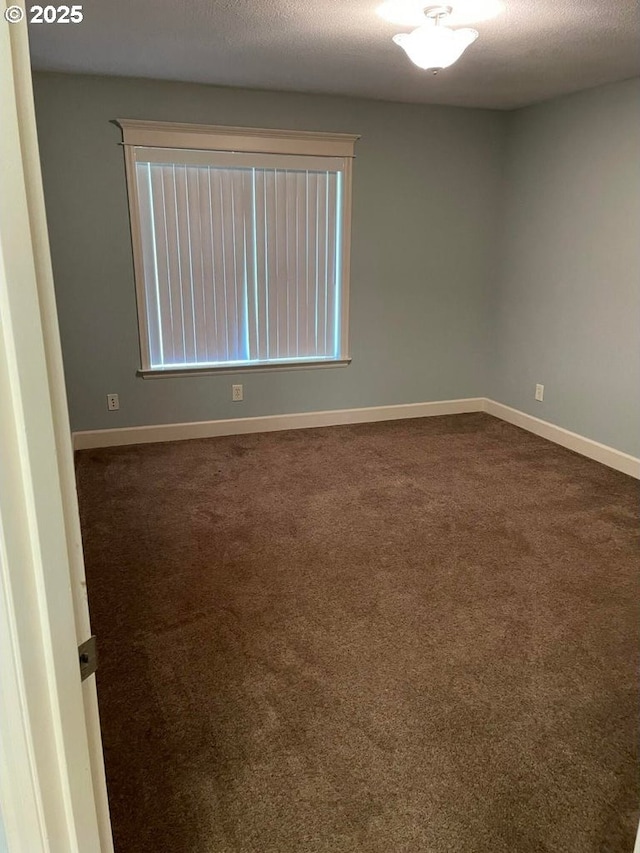 unfurnished room featuring baseboards, dark carpet, and a textured ceiling