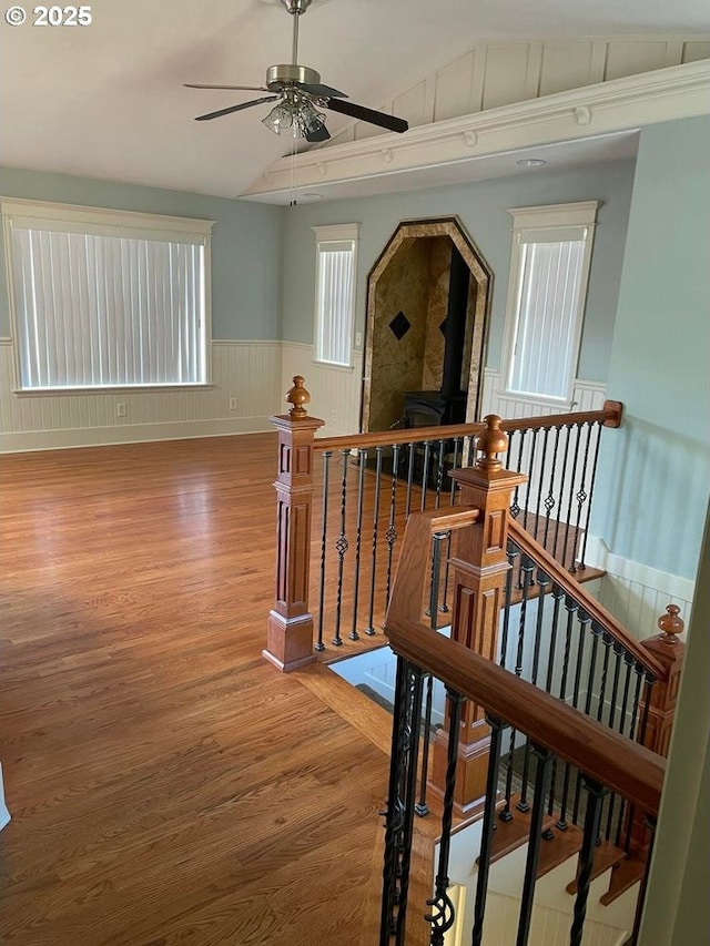 corridor featuring wainscoting, lofted ceiling, wood finished floors, and an upstairs landing