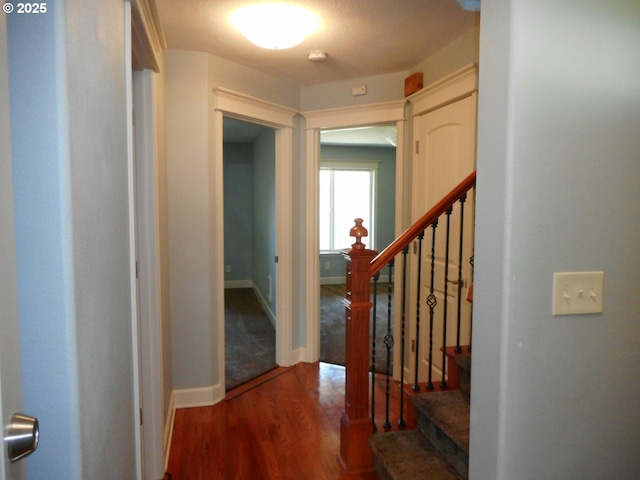 hallway featuring baseboards, wood finished floors, and stairway