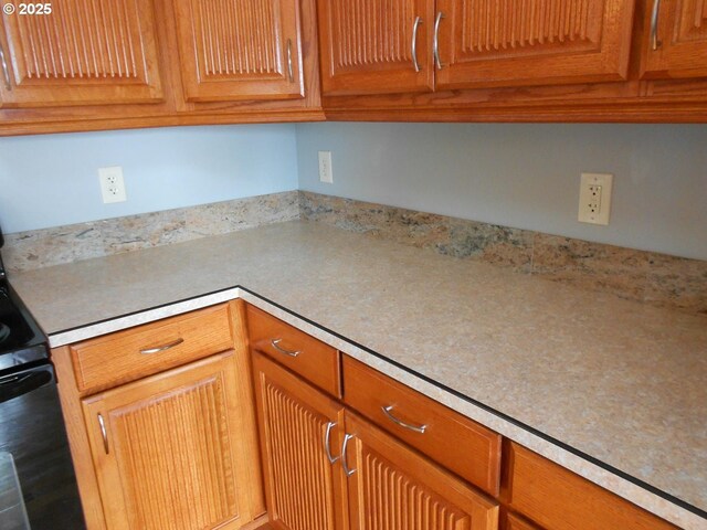 kitchen with light countertops, brown cabinets, and black electric range oven