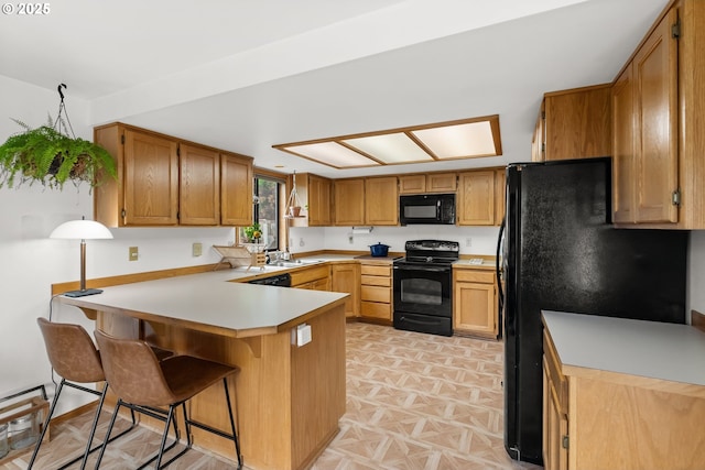 4131 Jessen Dr, Eugene, OR 97402 - kitchen with black appliances, a peninsula, light countertops, a breakfast bar area, and brown cabinetry
