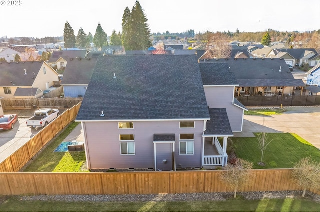 back of house with roof with shingles, fence private yard, and a residential view