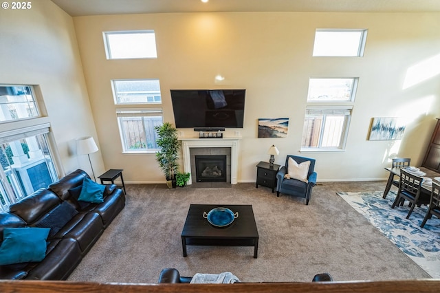 living area with a high ceiling, carpet, a fireplace, and baseboards