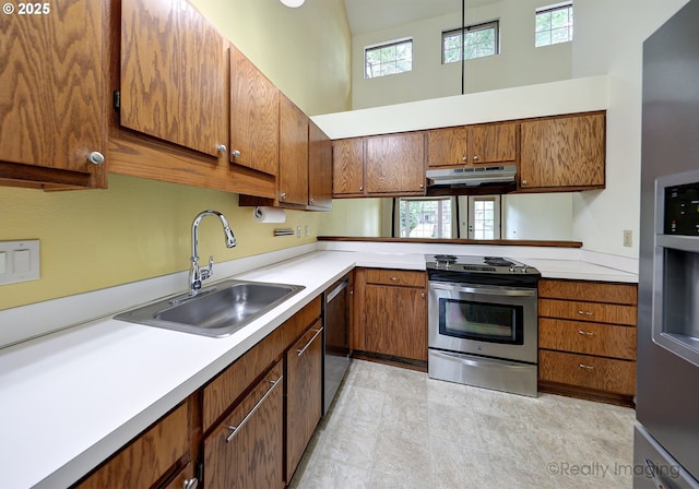 13775 SW Scholls Ferry Rd Unit 16, Beaverton, OR 97008 - kitchen featuring stainless steel appliances, under cabinet range hood, a towering ceiling, and brown cabinets
