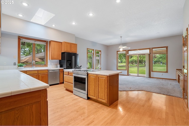 32680 SW Lake Point Ct, Wilsonville, OR 97070 - kitchen featuring stainless steel appliances, light wood-type flooring, a skylight, plenty of natural light, and recessed lighting